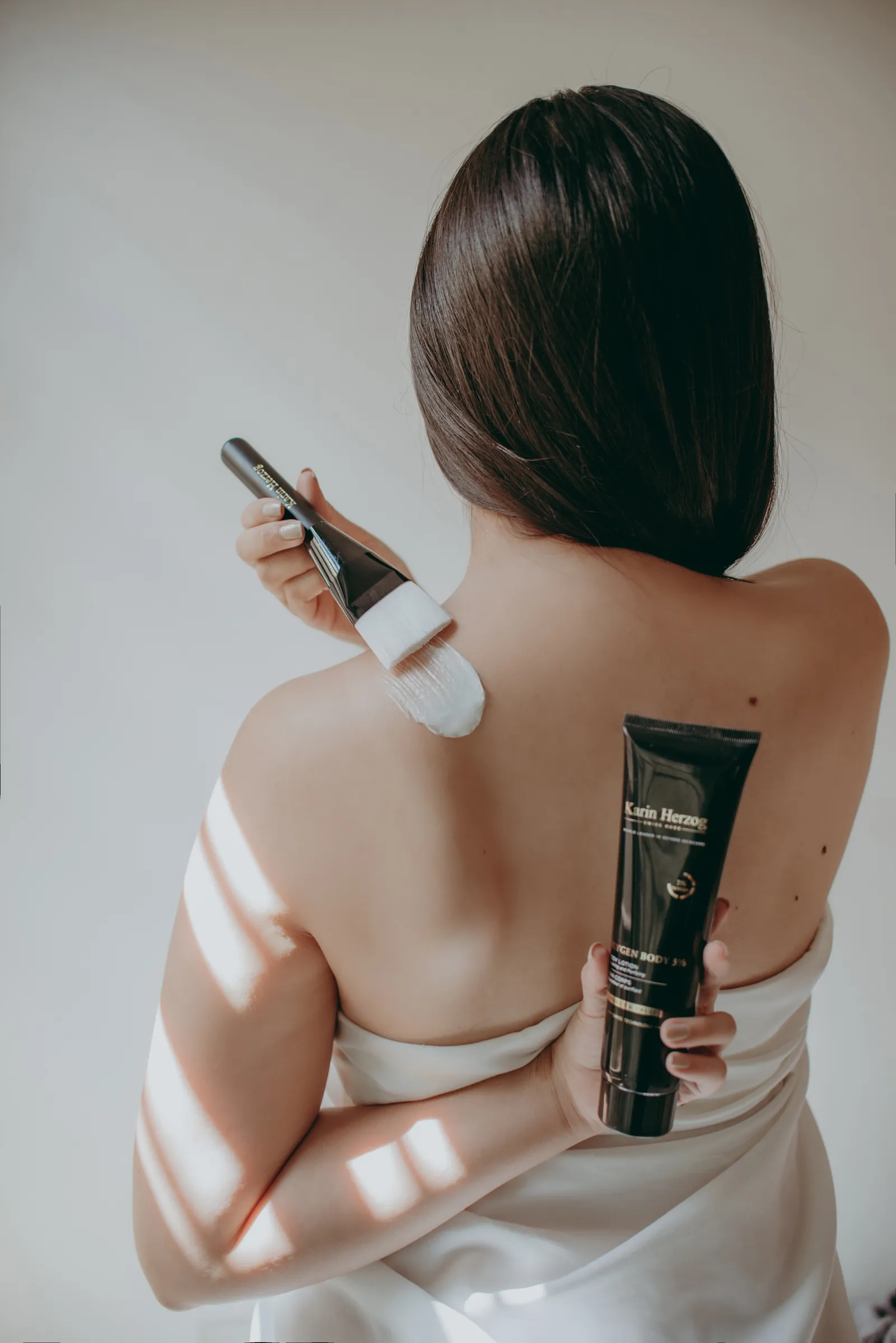 Auftragen mit dem Pinsel auf der Schulter, eine Tube Oxygen Body 3% in der Hand